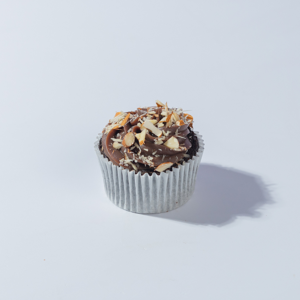Almond Milk Chocolate Cupcake Almond Milk Chocolate Cupcake in Vadodara topped with milk chocolate ganache, roasted almonds, and filled with almond praline by Le Fou Delight