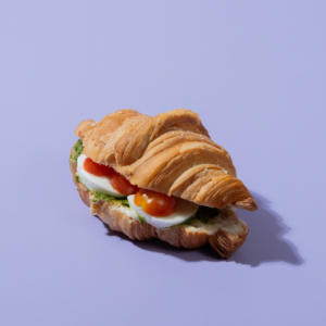 Savory Caprese croissant sliced open to show melted mozzarella cheese, fresh tomato, and green pesto filling
