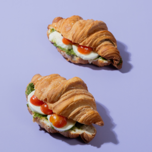 Savory Caprese croissant sliced open to show melted mozzarella cheese, fresh tomato, and green pesto filling