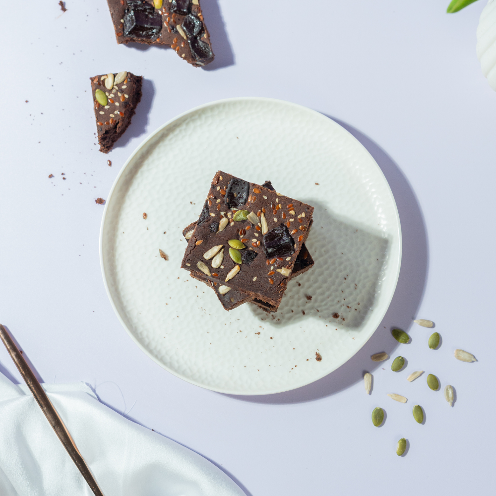 Fudgy gluten-free ragi chocolate brownie slice topped with healthy seeds