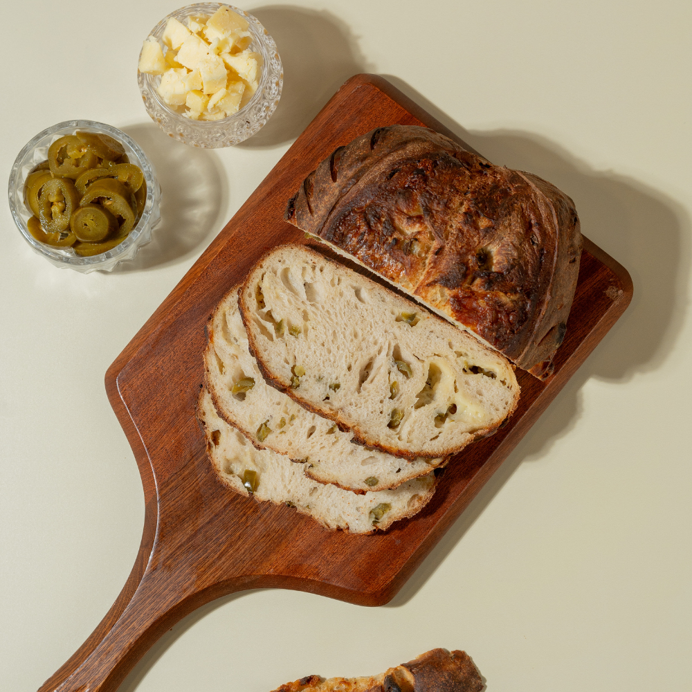 Sliced jalapeño cheddar cheese sourdough bread showing melted cheddar pockets and fresh jalapeño slices