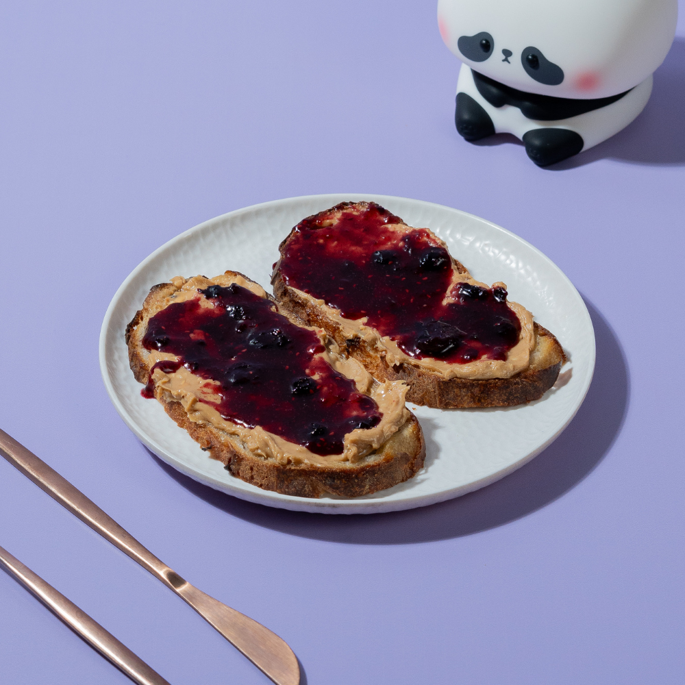 Toasted artisan sourdough slice loaded with peanut butter and rich berry fruit jam